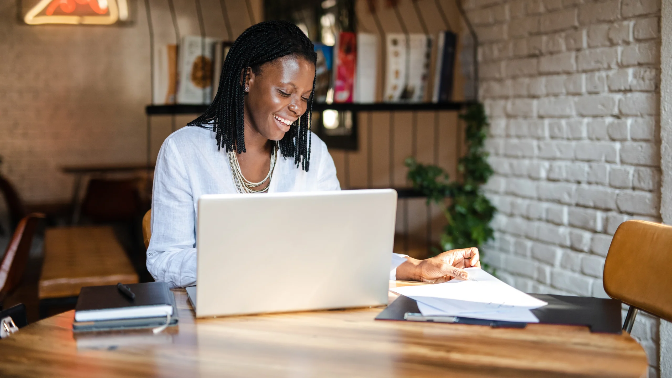 A faith-driven entrepreneur working on her laptop in a cozy workspace, reflecting on faith-based marketing strategies.